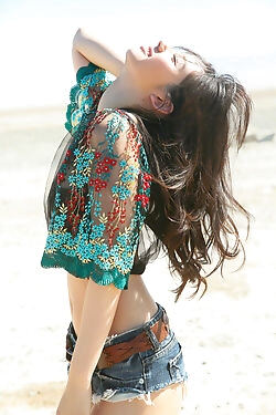 Süßes japanisches Mädchen auf den Strandstreifen unten zu ihrer schwarzen Unterkleidung ist untergegangen