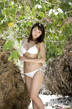 Милашка японка в белом бикини позирует на пляже